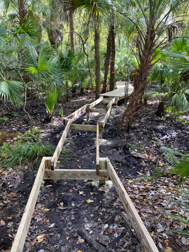 Boardwalk frame structure showing the wet, dark soil beneath that makes this section wet most of the year