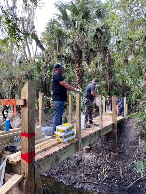 Children sitting on the edge of the finished Radio Crossing bridge watching the water below