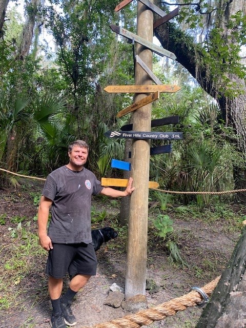 A volunteer on a ladder installing the River Hills weathervane at the top of the pole